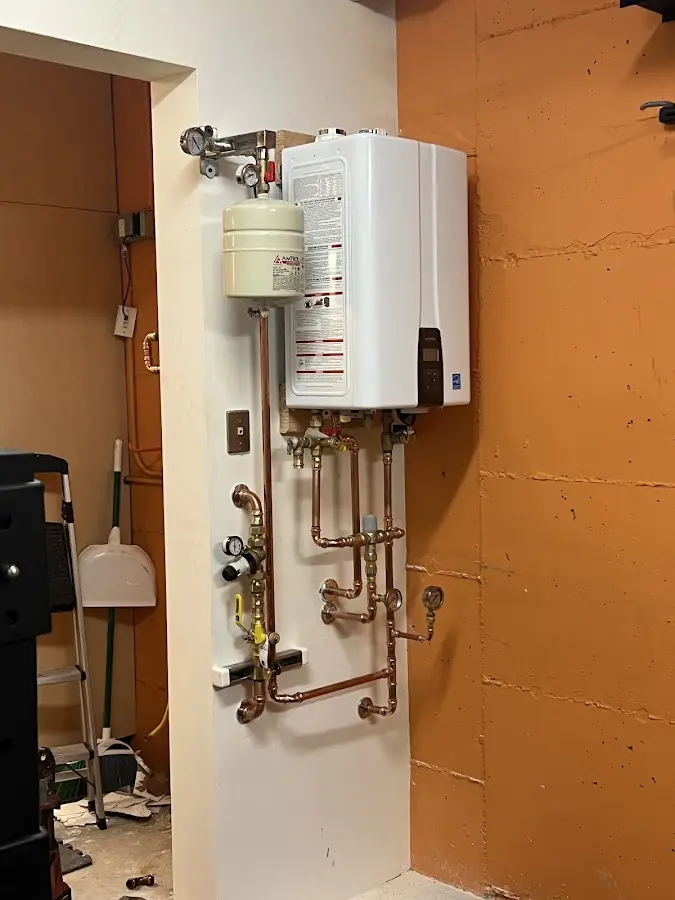 Plumbing technician inspecting water heater connections in Johnstown
